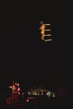 Acrobat on a higher ground with lighting filament and a violinist performing
