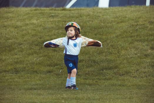 Little girl in helmet white shirt and blue shorts spreading arms