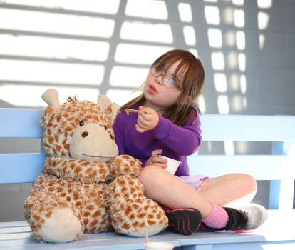 Girl w/ Down syndrome feeding icecream to toy