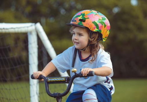 Girl wearing a floral helmet riding a bike at Little Dribblers football match