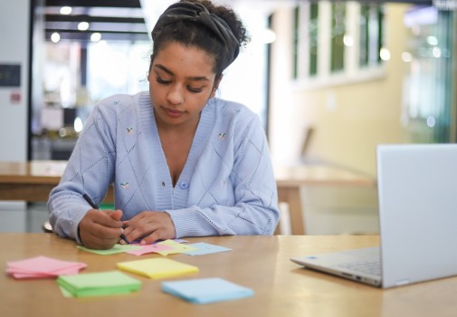 Girl writing on multi coloured notes
