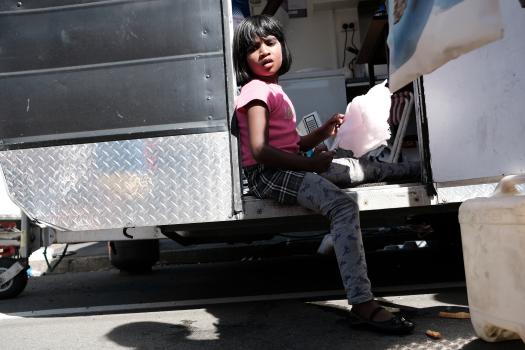 Little girl sitting in the door of a food truck eating cotton candy at Newtown festival 2021