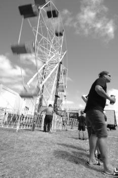 People next to a ferris-wheel at carnival black and white