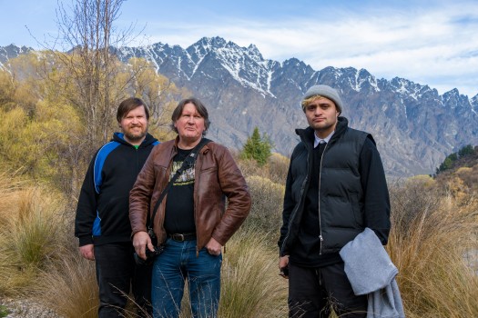 three men in front of mountains
