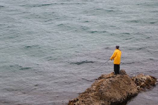 Person standing on a rock fishing