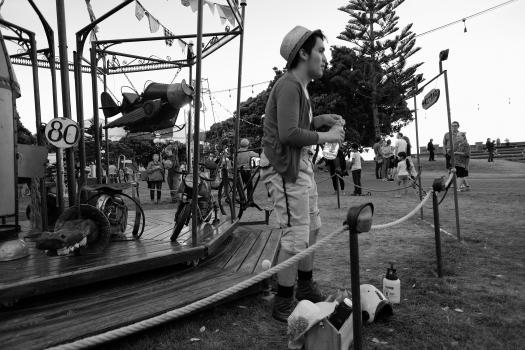 Guy with a hat next to a carousel ride black and white