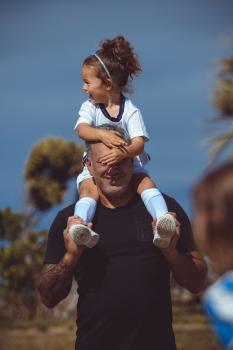 Daughter on dad's shoulders at Little Dribblers game