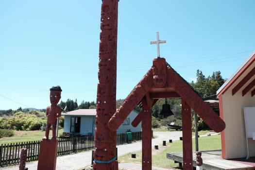 Maori carved totem pole sculpture and Church bell at Whakarewarewa