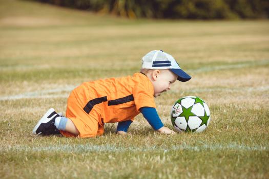 Toddler crawling on grass at Little Dribblers soccer event