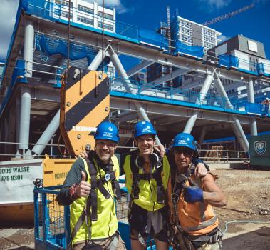 Three construction workers pose with thumbs up