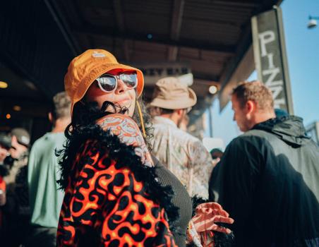 Tattooed woman dancing in an orange hat and shades at Newtown festival 2021