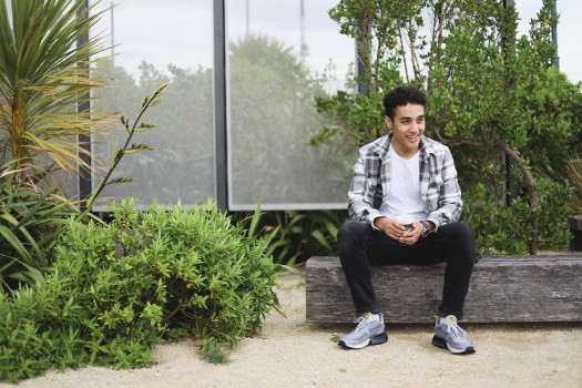 Young guy sitting next to plants outdoor