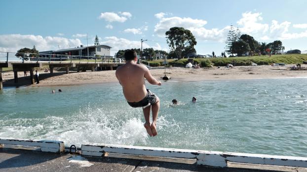 Boy jumping into water at the beach