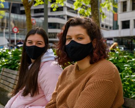 Women with masks on park bench