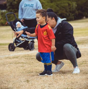 Mother pointing son towards football at Little Dribblers football competition