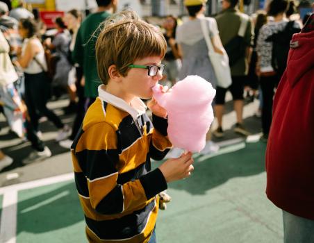 Nerdy kid in black and yellow shirt eating cotton candy at Newtown festival 2021