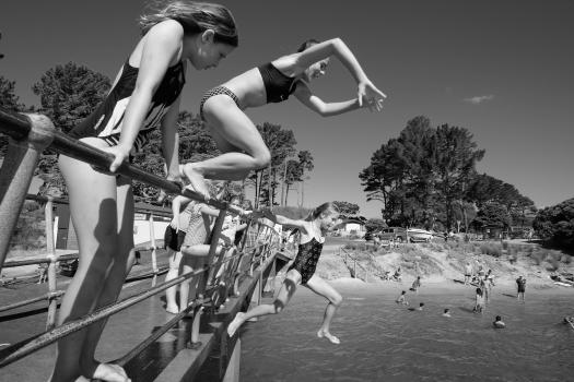 Girls Jumping into water off a pier black and white