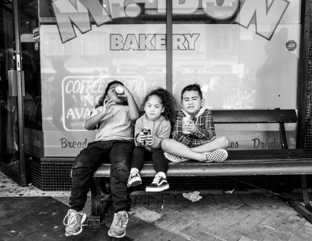 Three cute kids on a bench drinking soda at Newtown festival 2021 black and white