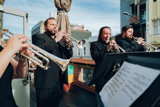Trumpet players performing outdoors in black clothes