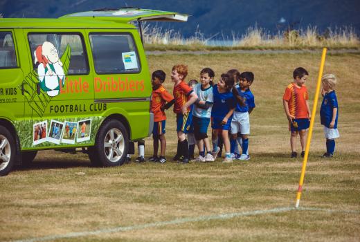 Kids waiting in line at a van at Little Dribblers football coaching