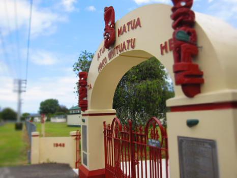 Red gate and cream arches of Marae near Pukehina