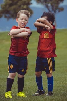 Two boys in red shirts and blue shorts at Little Dribblers football tournament