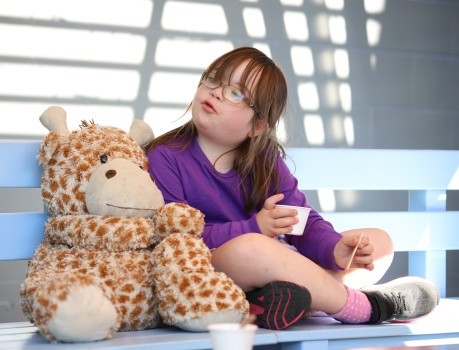 Child w/ Down syndrome cross legged with toy