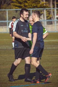 Smiling teammates shake hands at a football event - Sports Zone sunday league
