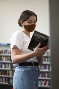 Girl wearing brown mask looking at a book