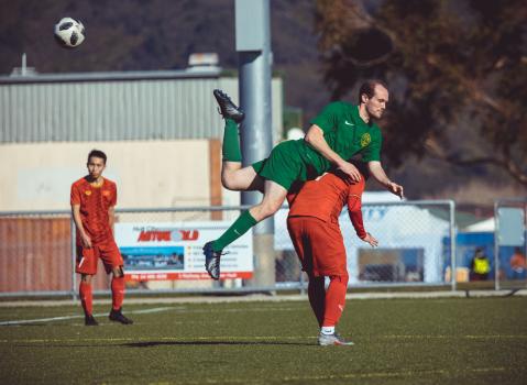 Player in green kit mounts opponent's shoulder during a jump - Sports Zone sunday league