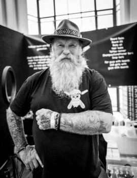 Old tattooed guy wearing a hat at Wellington tattoo convention 2021 monochrome