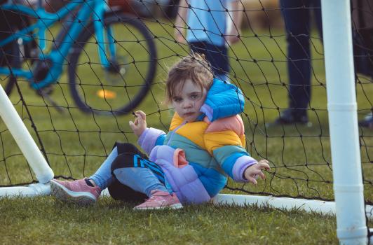 Little girl sitting inside goal post at Little Dribblers football match