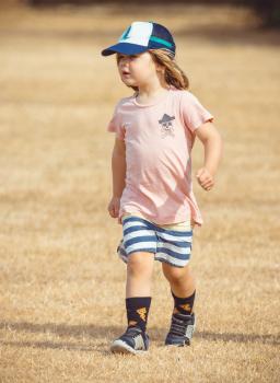 Girl wearing pink shirt with pirate symbol and striped shorts - Little Dribblers