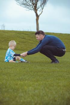 Father and son wearing blue shirts sitting on grass