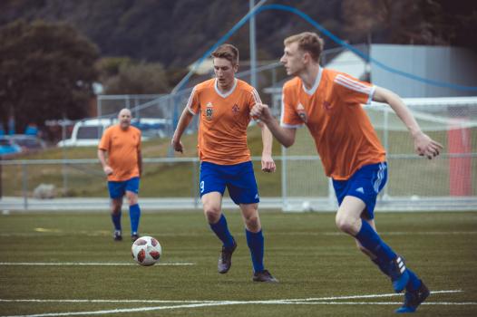 Players wearing orange Adidas jersey play football - Sports Zone sunday league