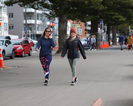 Two ladies walking on the beachfront pavement