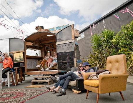 People sitting in and around a caravan at Newtown festival 2021