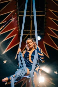 Circus performance by acrobat in blue attire with cloth rope