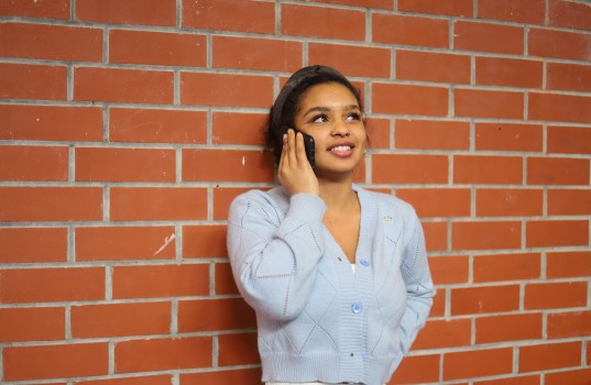 Lady on call next to brick wall