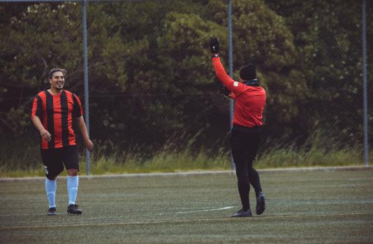 Referee wearing black Nike gloves signals for freekick - Sports Zone sunday league