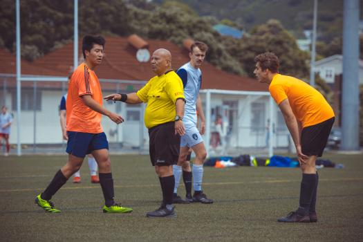 Referee in yellow shirt instructs a player - Sports Zone sunday league