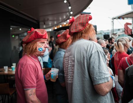 Men wearing Scottish caps and face paint flag 