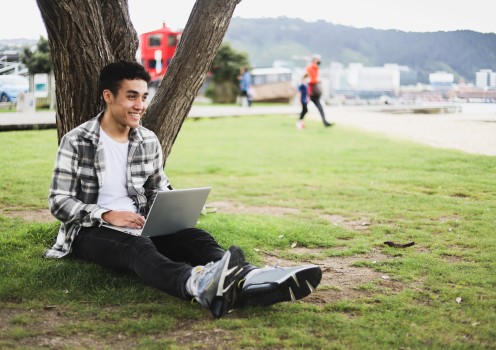 Guy in a park with laptop sitting under tree