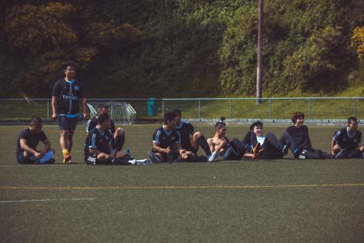 Teammates in black kit sit to watch penalty shoot out - Sports Zone sunday league