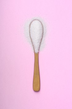 Stevia in a wooden spoon on pink background