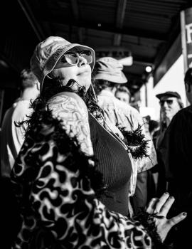Tattooed woman dancing in flame textured coat at Newtown festival 2021 monochrome