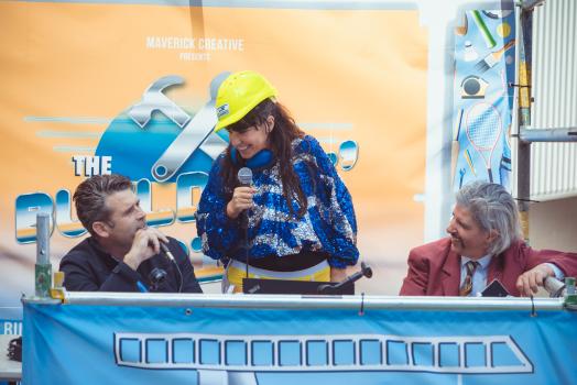 Woman wearing hard hat and sparkling jacket talking to commentators