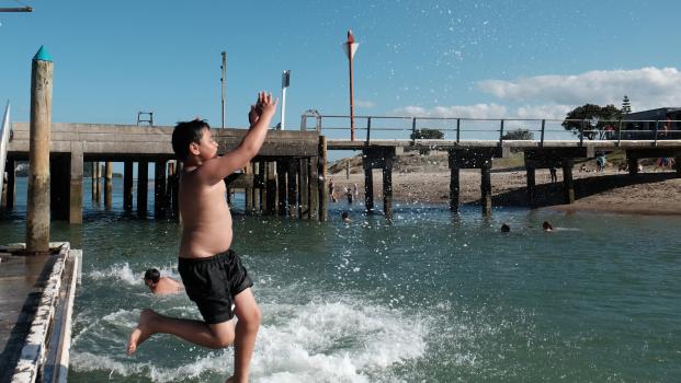 Kids jumping into water from pier at Whanagamata