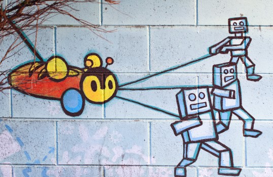 Robots tethering a bee artwork on a wall