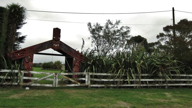 Maori carving Marae gate and flax bushes